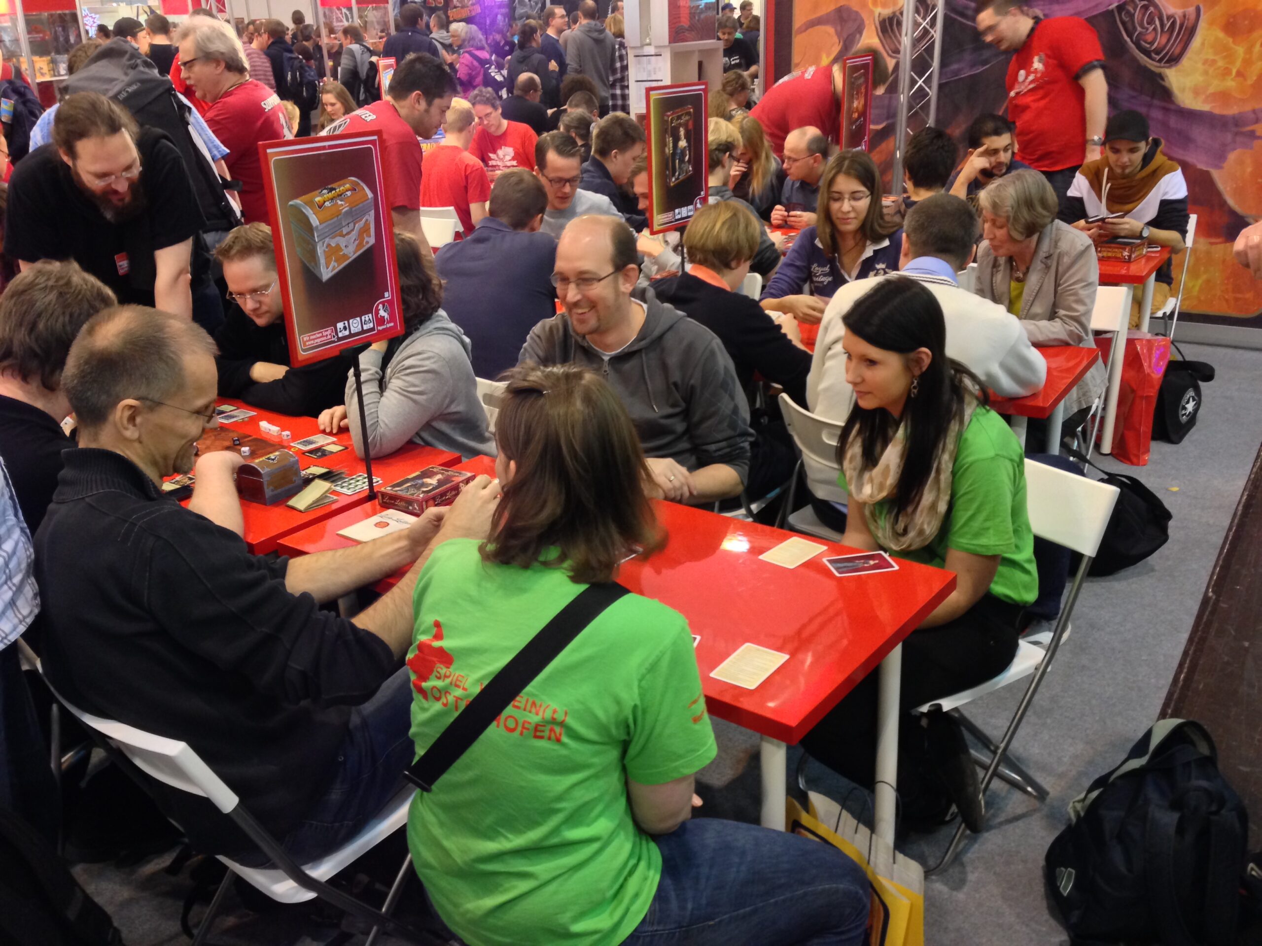 2 Frauen und 2 Männer sitzen an einen roten Tisch und testen das Spiel Love Letters