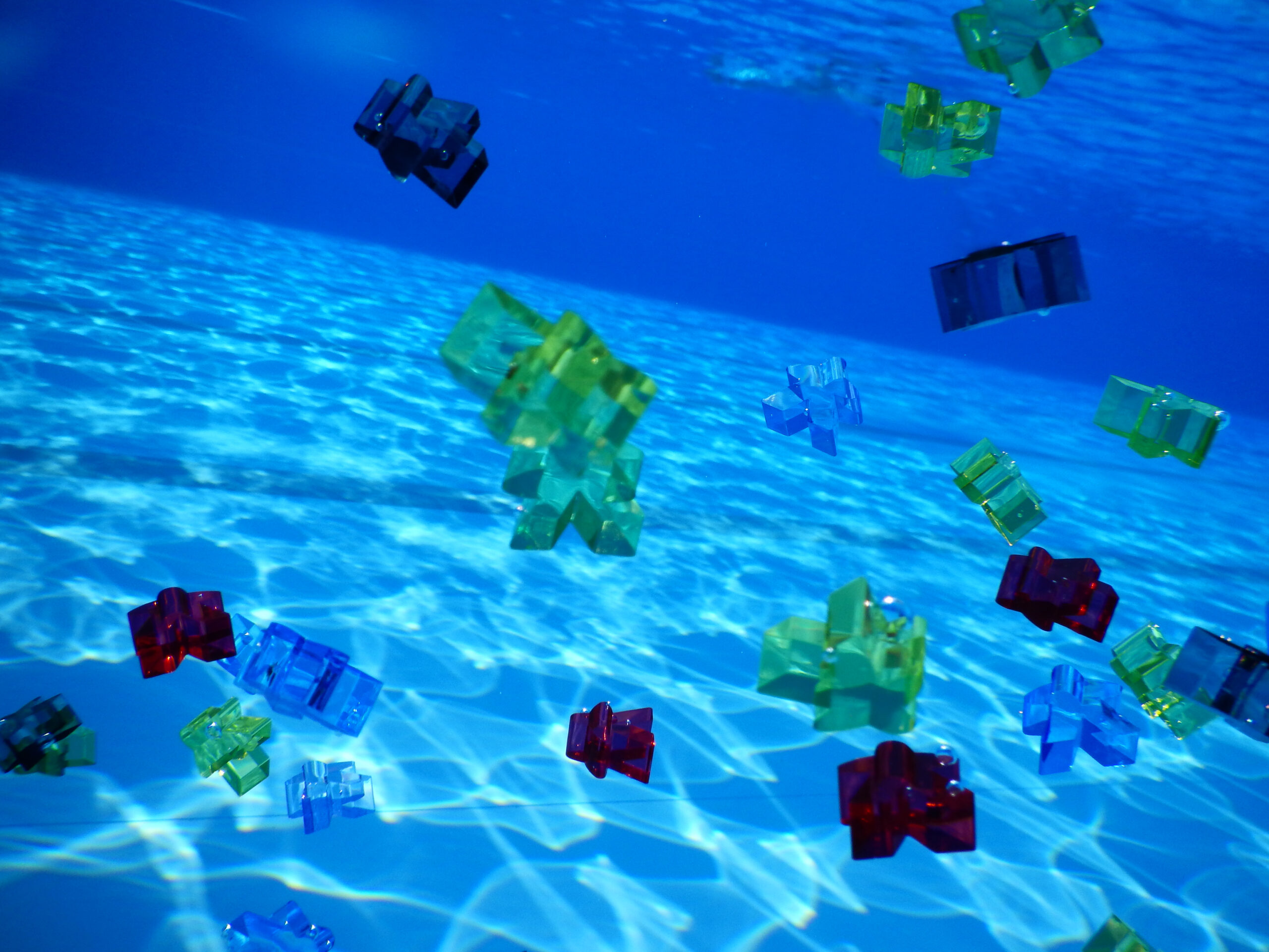 Bunte Spielfiguren aus Acryl die unter Wasser treiben